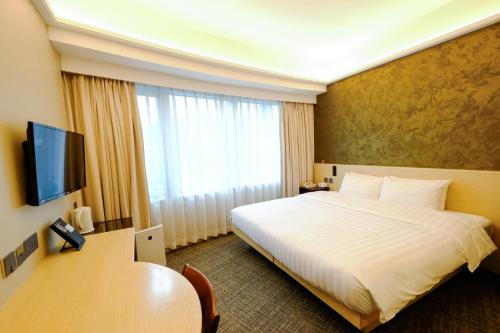 a hotel room with a large bed and a television at South Pacific Hotel in Hong Kong