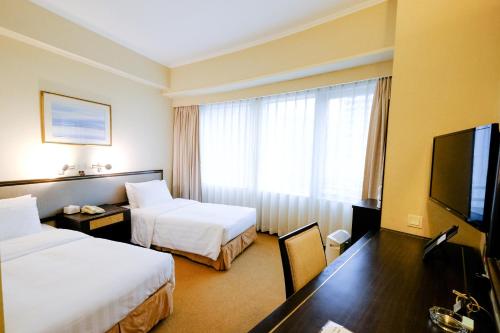 a hotel room with two beds and a flat screen tv at South Pacific Hotel in Hong Kong