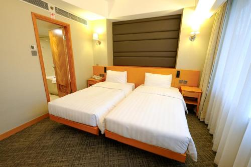 a hotel room with two beds and a mirror at South Pacific Hotel in Hong Kong