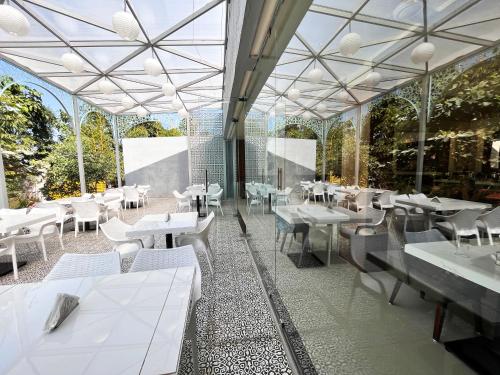 een restaurant met witte tafels, stoelen en ramen bij Olive Resort - Sillari Pench in Silāri