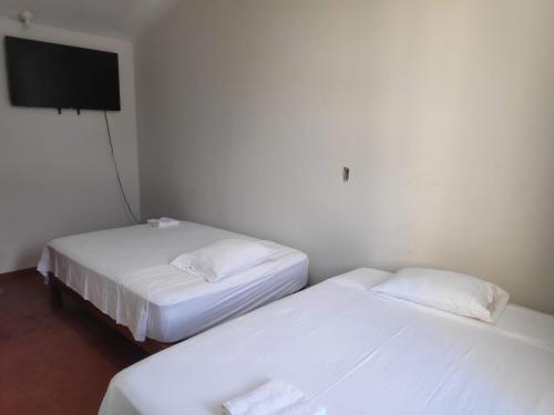 2 Betten in einem Zimmer mit einem TV an der Wand in der Unterkunft Amenli Lodging House in Piura