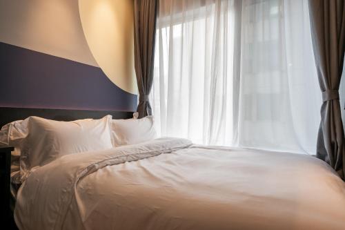 a bedroom with a white bed with a window at Dayin Youth Hostel - East Nanjing Road & People's Square & The Bund -Large Social Area -Bar -Café -Gym -Free Laundry Luggage Storage -24H Front Desk -English Service in Shanghai
