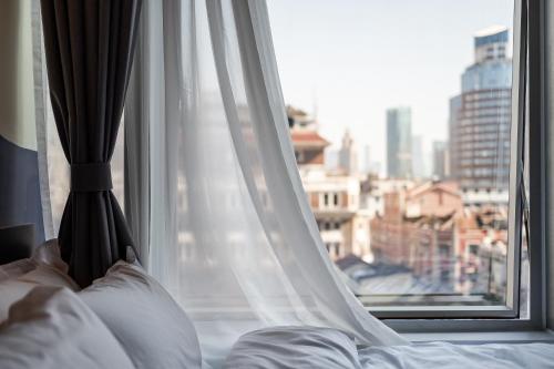 a bed with a window with a view of a city at Dayin Youth Hostel - East Nanjing Road & People's Square & The Bund -Large Social Area -Bar -Café -Gym -Free Laundry Luggage Storage -24H Front Desk -English Service in Shanghai