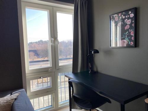 a desk in a room with two windows and a table at Magnolia House Norrviken in Sollentuna