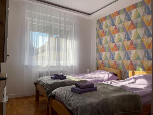 2 Betten in einem Zimmer mit lila Handtüchern darauf in der Unterkunft Apartman MDB in Subotica