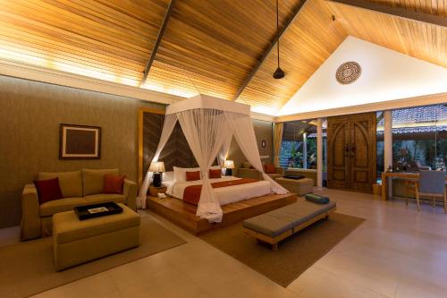 a bedroom with a bed and a couch in a room at Plataran Borobudur in Borobudur