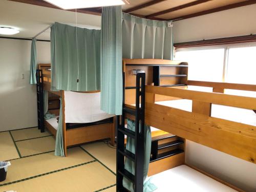 指宿市にあるゲストハウスまちかど Guest House MACHIKADOの二段ベッド2台と窓が備わる客室です。