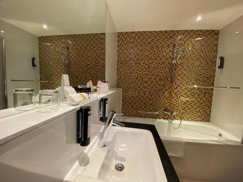 a bathroom with a tub, sink and mirror at Boutique Hotel Das Tigra in Vienna