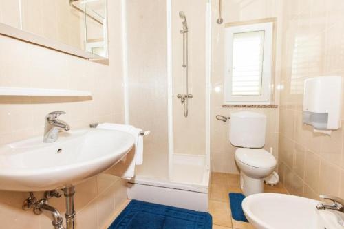 een witte badkamer met een wastafel en een toilet bij B&B Pansion Vago in Malinska
