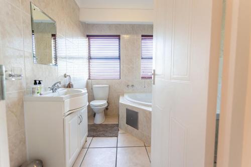 a bathroom with a sink and a toilet and a tub at Langebaan Golf Lagoon Haven in Langebaan