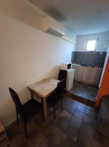 a room with a table and chairs and a kitchen at Vasti Apartman in Siófok