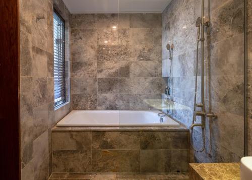 a bathroom with a bath tub and a window at Nghê Prana Hotel and Spa Hoi An in Hoi An