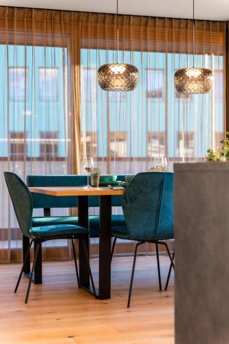 a dining room with a table and chairs and windows at Rienz Alpine City Lofts in Brunico
