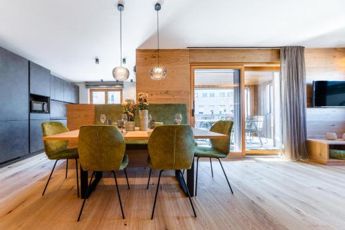 Rienz Alpine City Lofts في برونيكو: غرفة طعام مع طاولة خشبية وكراسي خضراء