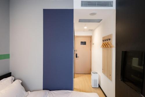 a bedroom with a blue accent wall and a bed at Dayin Youth Hostel - East Nanjing Road & People's Square & The Bund -Large Social Area -Bar -Café -Gym -Free Laundry Luggage Storage -24H Front Desk -English Service in Shanghai