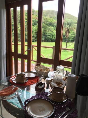 a table with plates of food on a table in front of a window at Chalé Águas Claras in Capitólio