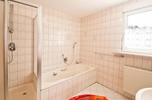 a white tiled bathroom with a tub and a window at Ferienwohnung Jessica in Geroldsgrün