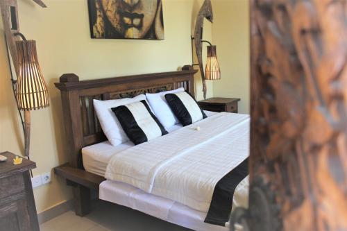 a bedroom with a bed with black and white pillows at Silvy Guesthouse in Canggu