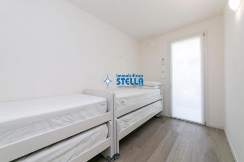 biała sypialnia z białymi łóżkami i oknem w obiekcie Villaggio Le Tropezien w mieście Lido di Jesolo