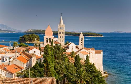 a town on a hill with a church and the ocean at Modern Oceanview in Metajna