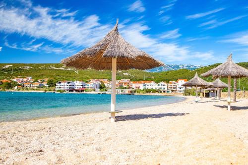 a beach with straw umbrellas and the water at Modern Oceanview in Metajna