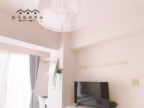a living room with a tv and a chandelier at OUCHI HOTEL Fujimi in Hiroshima