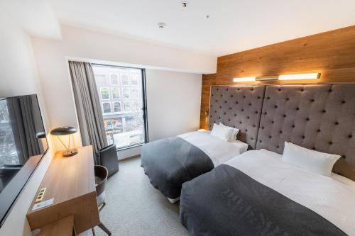 a hotel room with two beds and a window at THE KNOT SAPPORO in Sapporo
