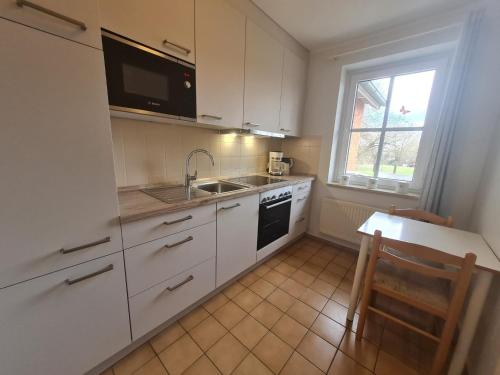 uma cozinha com armários brancos, um lavatório e uma janela em "Pappelhof - Whg 3" em Grömitz