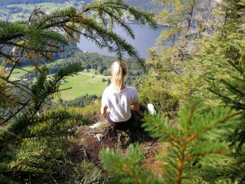 a woman sitting on a hill looking at a valley at Appartement-Pension Familie Gewessler in Bad Mitterndorf