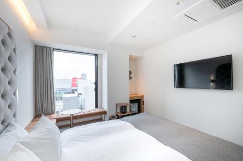 a hotel room with a bed and a television at THE KNOT SAPPORO in Sapporo