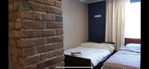 a bedroom with two beds next to a brick wall at Delta 8 - two big beds in Tartu