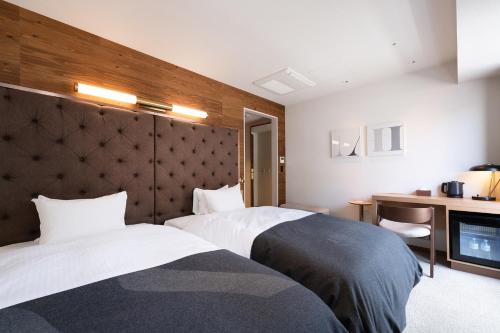 a hotel room with two beds and a television at THE KNOT SAPPORO in Sapporo