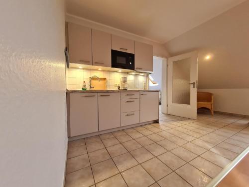 a kitchen with white cabinets and a tiled floor at "Pappelhof - Whg 8" in Grömitz