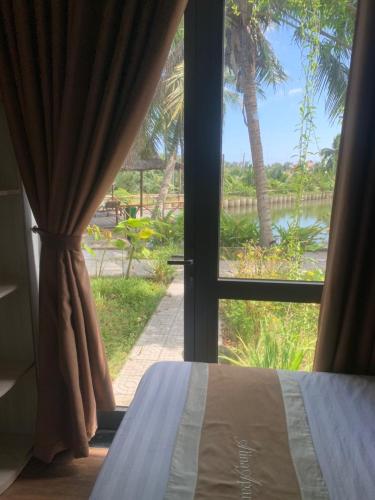 a bedroom window with a view of a palm tree at Alina Retreat in Hiếu Nhơn