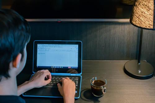 a young boy typing on a laptop computer on a table at First Hotel Jörgen Kock in Malmö