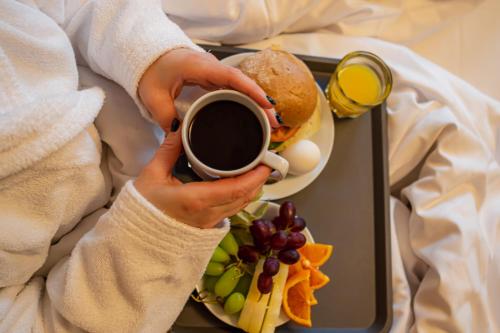 a person holding a cup of coffee and a tray of food at First Hotel Jörgen Kock in Malmö