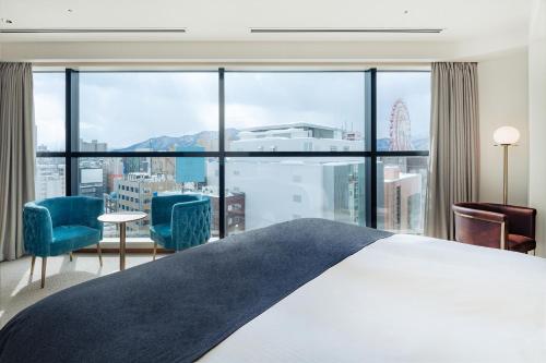 a bedroom with a bed and a large window at THE KNOT SAPPORO in Sapporo