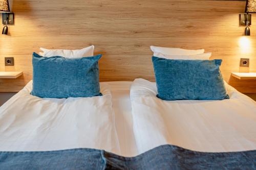 a bed with two blue pillows on top of it at First Hotel Jörgen Kock in Malmö