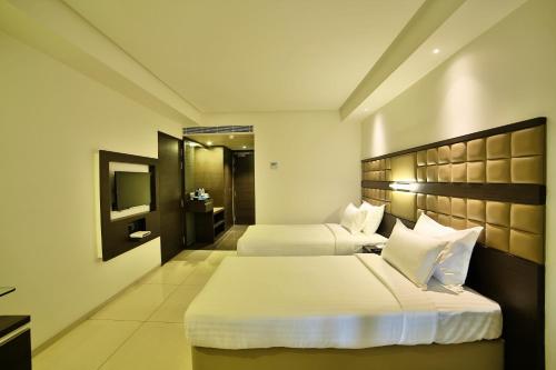 a hotel room with two beds and a television at HOTEL G EXPRESS Formerly Known as TGB Express in Ahmedabad