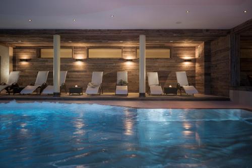 a pool in a hotel with chairs and a swimming pool at Bachmanngut in St. Wolfgang