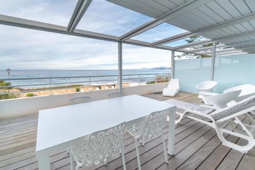 a white dining room with a view of the ocean at Résidence Dary in LʼÎle-Rousse