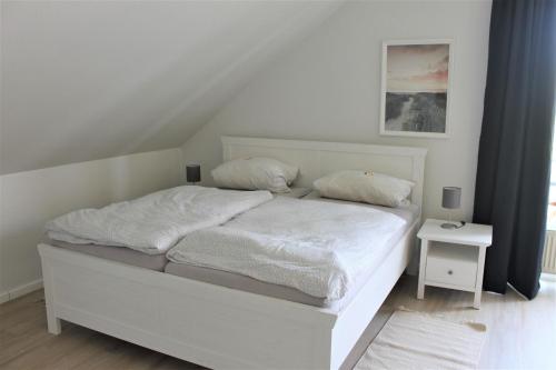 uma cama branca com duas almofadas num quarto em "Pappelhof - Whg 10" em Grömitz