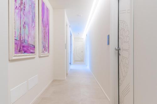 a hallway with white walls and pink paintings on the walls at Relais Forte Benedek Wine & SPA - Adults Only in Pastrengo