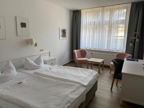 a hotel room with a white bed and chairs at Norddeutscher Hof in Stralsund