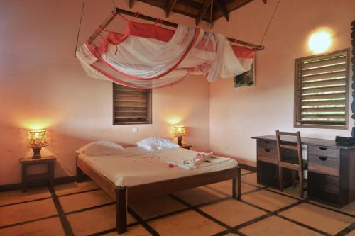 una camera con letto a baldacchino e scrivania di Hotel Benjamin ad Ambatoloaka
