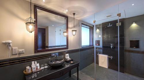 a bathroom with a sink and a shower with a mirror at Niraamaya Wellness Retreats Backwaters And Beyond Kumarakom in Kumarakom