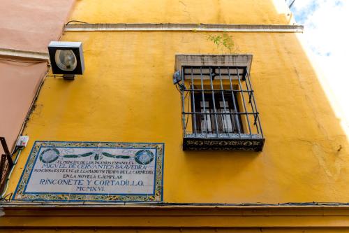 un edificio amarillo con una ventana y un cartel en él en Casa Ispal Alfalfa, en Sevilla