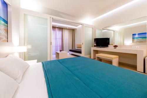 a hotel room with a large bed and a television at Lindos White Hotel & Suites in Líndos