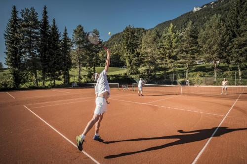 a man serving a tennis ball on a tennis court at Bachmanngut in St. Wolfgang
