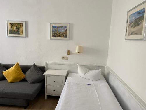 
a living room with a bed, couch and a painting on the wall at Norddeutscher Hof in Stralsund
